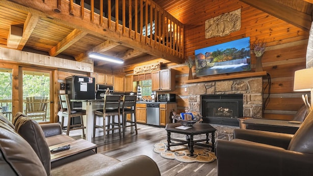 Un interior de cabaña con sala de estar, cocina y chimenea.