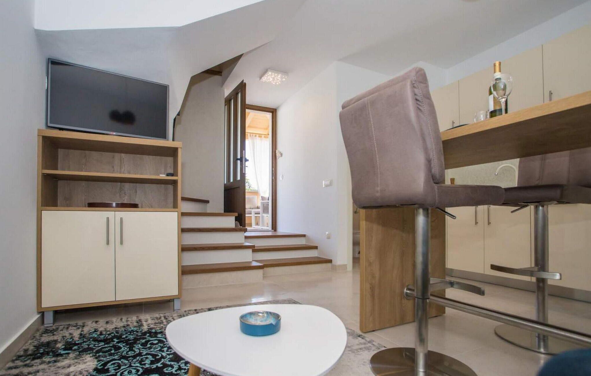 Un salon moderne avec un téléviseur, une table basse ronde, un canapé et un escalier menant à une autre pièce.