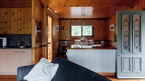 A cabin interior with a kitchen area, a dining space, and a living room with a sofa.
