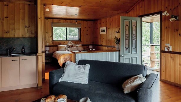 A cozy cabin interior with a dining area, a sofa, and a kitchen.