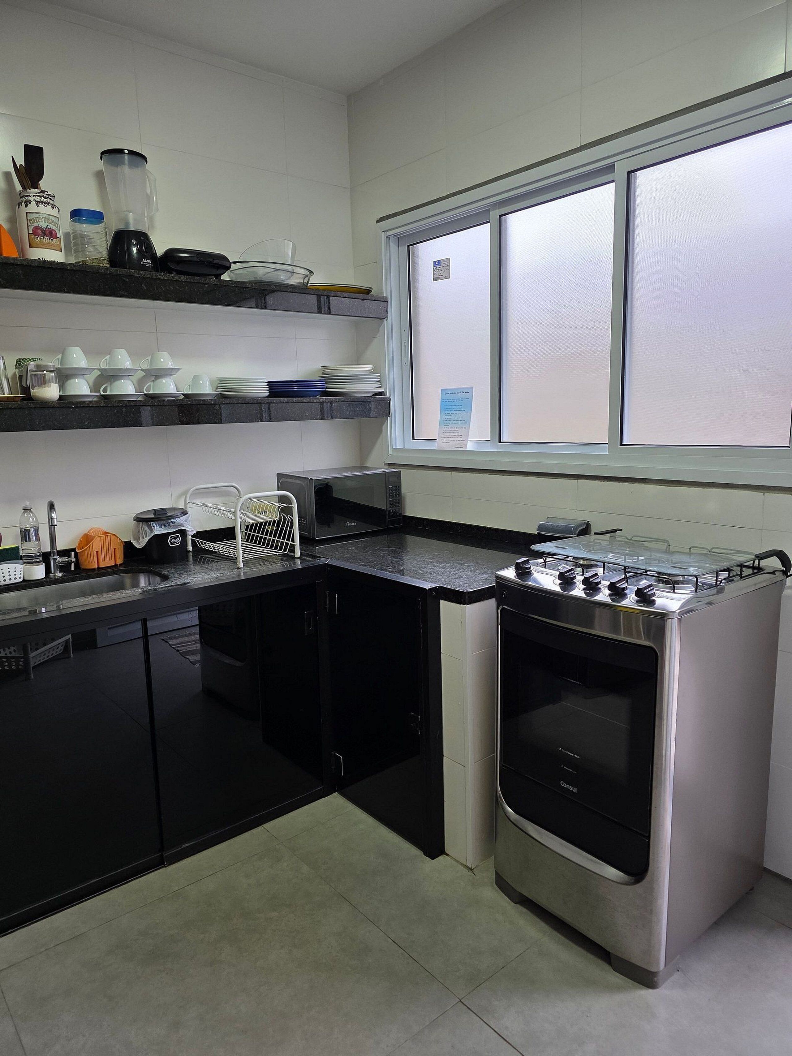 A modern kitchen with black cabinets, a stainless steel stove, and a window above the sink.