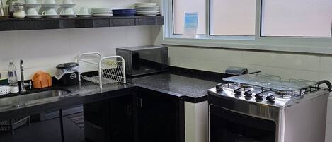 A modern kitchen with black cabinets, a stainless steel stove, and a window above the sink.