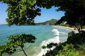 A coastal landscape with clear blue waters, a sandy beach, and lush greenery. - Chalé 5 (Ubatuba)