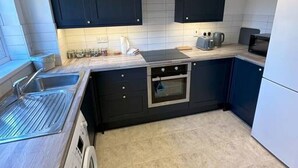 A modern kitchen with dark cabinets, a built-in oven, a microwave, and a stainless steel sink.