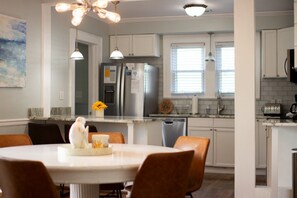 A modern kitchen with white cabinets, stainless steel appliances, and a dining area with a round table and chairs.