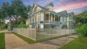 Ein zweigeschossiges Haus mit Veranda, umzäunter Garten und Auffahrt.