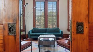Ein Zimmer mit einem grünen Sofa, einem runden Couchtisch, einer Stehlampe und einem Teppich mit Muster.
