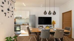 A modern kitchen with white cabinets, a built-in oven, and a dining area with a wooden table and four chairs. - 2 bedroom nice home in Vodnjan (Vodnjan)