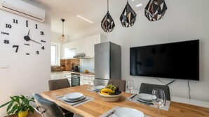 A modern dining area with a wooden table, chairs, a bowl of fruit, and a flat-screen TV mounted on the wall. - 2 bedroom nice home in Vodnjan (Vodnjan)