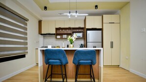 Une cuisine moderne avec deux tabourets de bar bleus, un réfrigérateur blanc et des meubles de rangement en bois.
