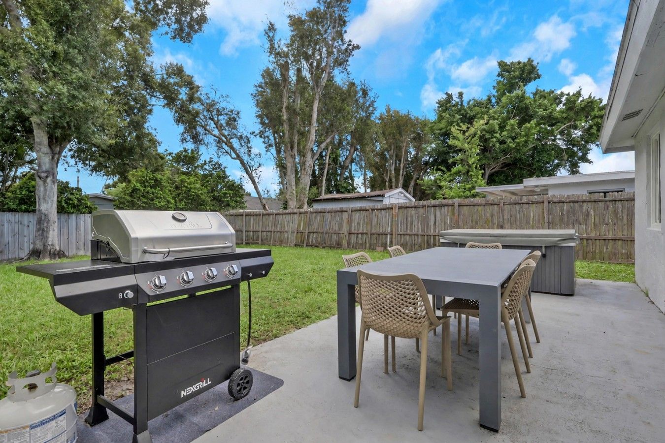 Une terrasse extérieure avec un barbecue, une table et des chaises.