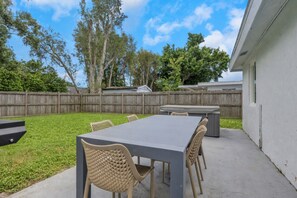 A patio with a table and chairs, a barbecue grill, and a wooden fence in the background. - Fenced in w/ Jacuzzi Close to Siesta Key Bridge (Sarasota)