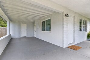 A covered patio area with a concrete floor, white walls, and a door leading to the interior. - Fenced in w/ Jacuzzi Close to Siesta Key Bridge (Sarasota)