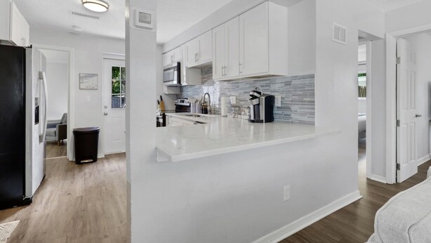 A modern kitchen with white cabinetry, a marble countertop, and a built-in microwave.