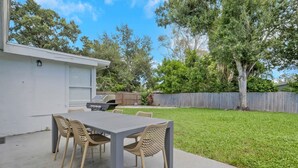 A patio with a table and chairs, a grill, and a fenced yard.