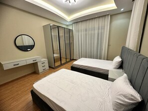 A modern bedroom with two beds, a walk-in closet, and a large mirror. - Villa With Private Pool In Beverly Hills comp -Allegria residence-Sheikh Zayed (Giza Governorate)