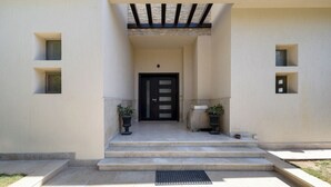 A building entrance with a black door, steps, potted plants, and a covered porch area. - Villa With Private Pool In Beverly Hills comp -Allegria residence-Sheikh Zayed (Giza Governorate)