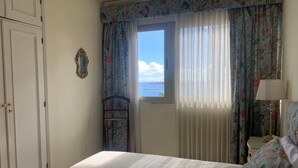 A bedroom with a bed, a window with curtains, a nightstand, and a lamp. - Azul y mar (Las Palmas de Gran Canaria)