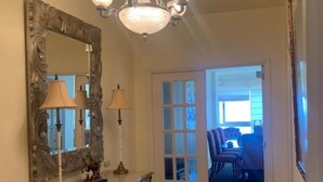 A hallway with a chandelier, a mirror, and a checkered console table. - Azul y mar (Las Palmas de Gran Canaria)
