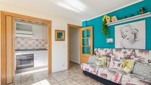 A kitchen with a built-in oven, a dining area with a sofa, and a wall with a Paris-themed artwork.