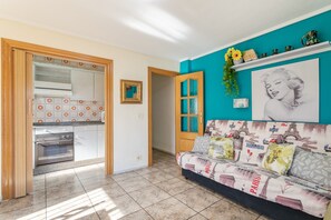 A kitchen with a built-in oven, a dining area with a sofa, and a wall with a Paris-themed artwork.