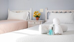 A neatly made bed with a towel and toiletries, a nightstand with a vase of sunflowers, and a wall-mounted artwork.