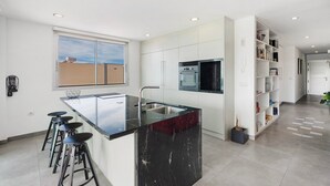 A modern kitchen with a central island, bar stools, a built-in oven, and a large window. - Holiday Villa 'Tulio Homme 2' with Sea Views, Private Pool and Wi-Fi (Adeje)