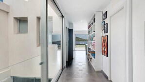 A corridor with a glass wall, a bookshelf with framed pictures, and a door leading to a room. - Holiday Villa 'Tulio Homme 2' with Sea Views, Private Pool and Wi-Fi (Adeje)