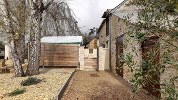 A courtyard with a wooden gate, stone walls, and a gravel path.