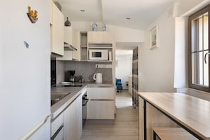 A compact kitchen with a microwave, coffee maker, and cabinets.