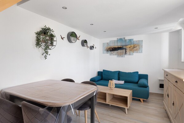 A modern living space with a dining table, chairs, a sofa, and a cabinet.
