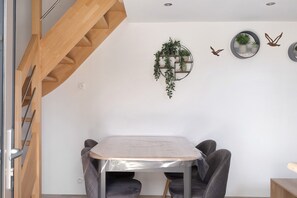 Un interior moderno con una escalera de madera, una estantería con plantas en la pared y un espejo redondo.