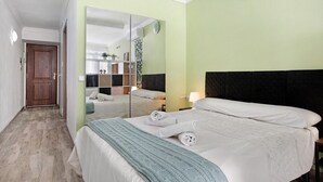 Een hotelkamer met een bed, een spiegel, een nachtkastje en een deur.