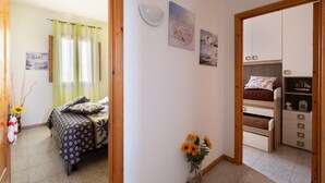Un dormitorio con cama, mesita de noche, cómoda y una pequeña mesa con un florero.