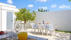 An outdoor dining area with a table set for two, a pitcher of orange juice, and a bottle of wine. - Villa 'Maestrale Torre Lapillo' with Private Terrace, Wi-Fi and Air Conditioning (Porto Cesareo)