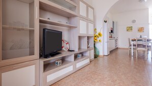 A modern kitchen with a dining area, wooden cabinets, and a TV. - Villa 'Maestrale Torre Lapillo' with Private Terrace, Wi-Fi and Air Conditioning (Porto Cesareo)
