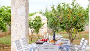 An outdoor dining table with white chairs, a stone pillar, and a tablecloth with a blue and white pattern. - Villa 'Perla Marina Luxury' with Sea View, Wi-Fi and Air Conditioning (TOTTE LAPILLO)