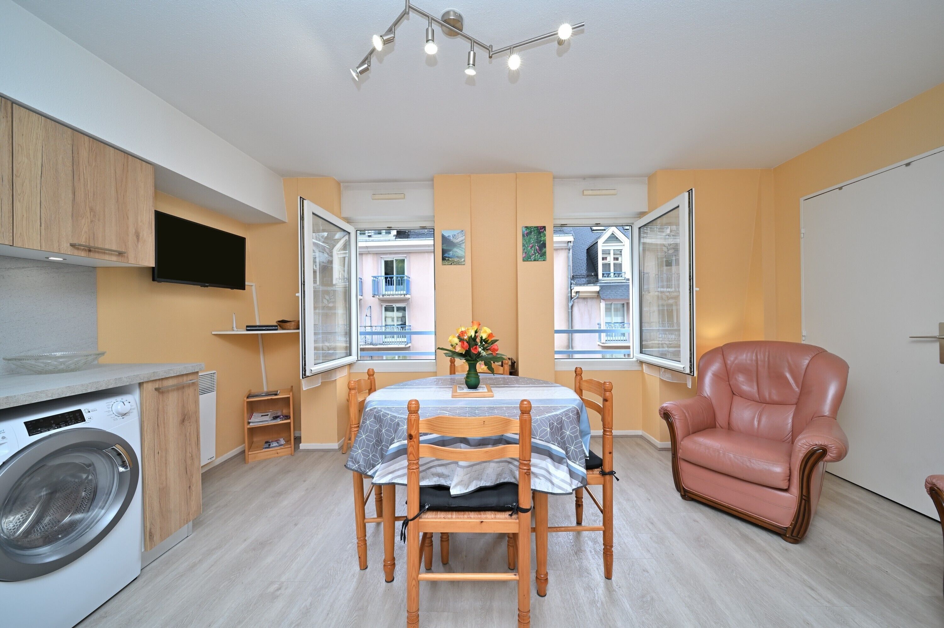 Un espacio habitable compacto con zona de comedor, lavadora y una silla.