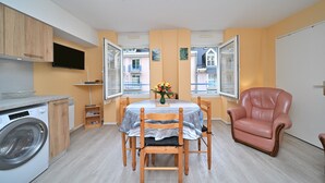 A compact living space with a dining area, a washing machine, and a chair. - Central Cauterets, Private Parking, Walk to Thermal Baths & Ski Lifts (Cauterets)