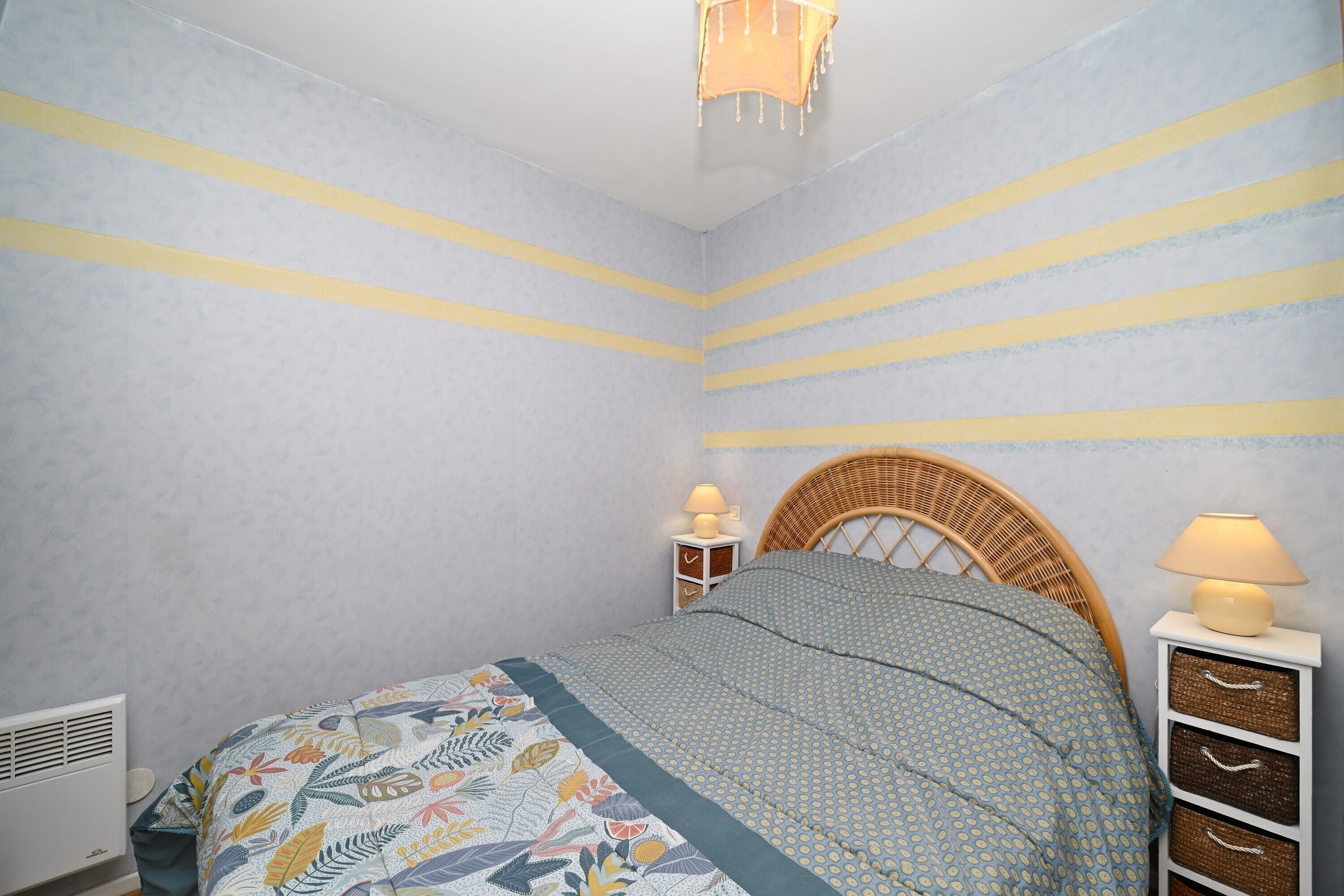 Una camera da letto con un letto, due comodini, una lampada a parete e un lampadario.