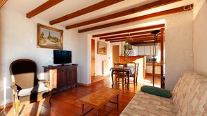 A living room with a sofa, a wooden table, a TV on a cabinet, and a painting on the wall. - Studio Apartment 'Ukika' with Sea View, Wi-Fi and Air Conditioning (cassis)