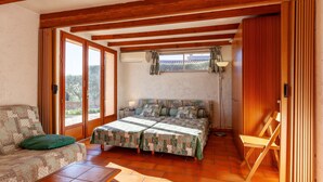 A room with a wooden ceiling, a bed with a patterned bedspread, a sofa with a green cushion, and a chair. - Studio Apartment 'Ukika' with Sea View, Wi-Fi and Air Conditioning (cassis)