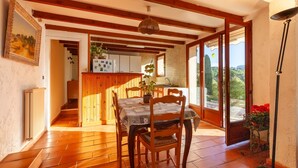 A dining area with wooden chairs and a table, a kitchen in the background, and a view through a glass door. - Studio Apartment 'Ukika' with Sea View, Wi-Fi and Air Conditioning (cassis)