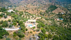 Ein Haus mit Pool, umgeben von Bäumen und Hügeln.