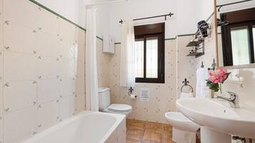 A bathroom with a bathtub, toilet, bidet, and sink.