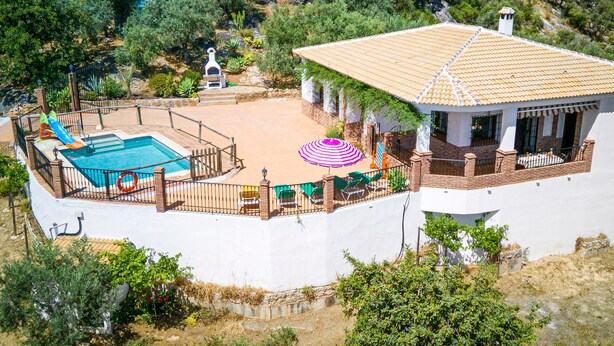 Eine Villa mit Swimmingpool, Gartenmöbeln und einem Garten.