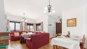 Ein Essbereich mit einem für vier Personen gedeckten Tisch, einem roten Sofa und einer Kristallleuchtre.