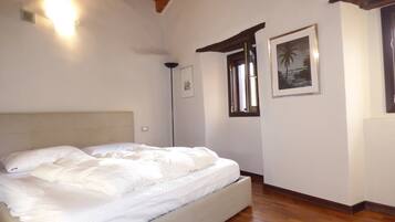 Un dormitorio con cama, rejilla en el techo, luz empotrada en la pared, cuadro enmarcado y ventana con vistas.