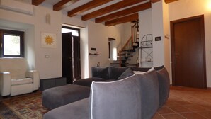 A living room with a sofa, a chair, a staircase, and a door.