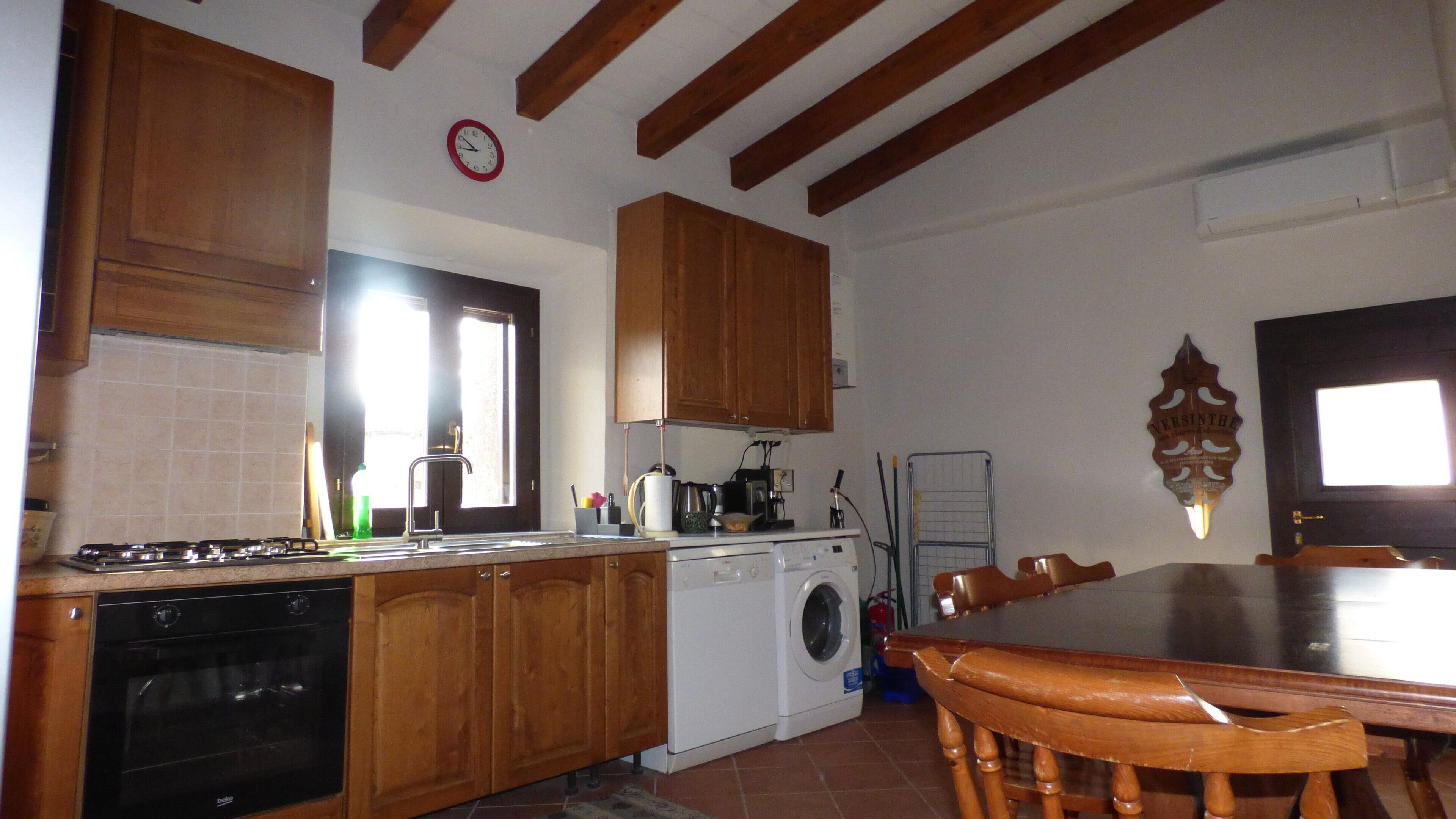 A kitchen with wooden cabinets, a stove, a dishwasher, and a dining table with chairs.